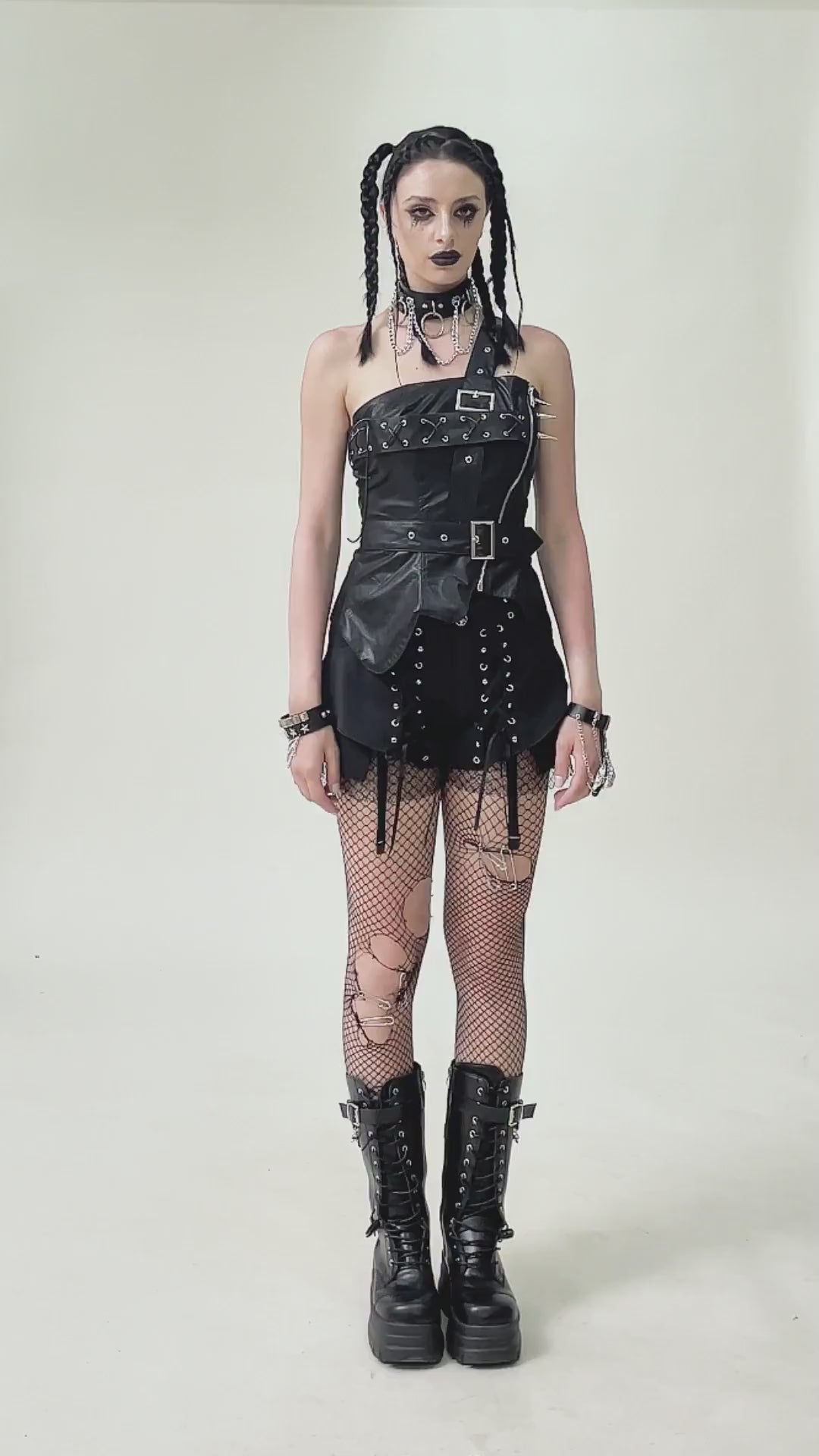 Punk corset top with spiked details, zipper closure, paired with fishnet stockings and combat boots.