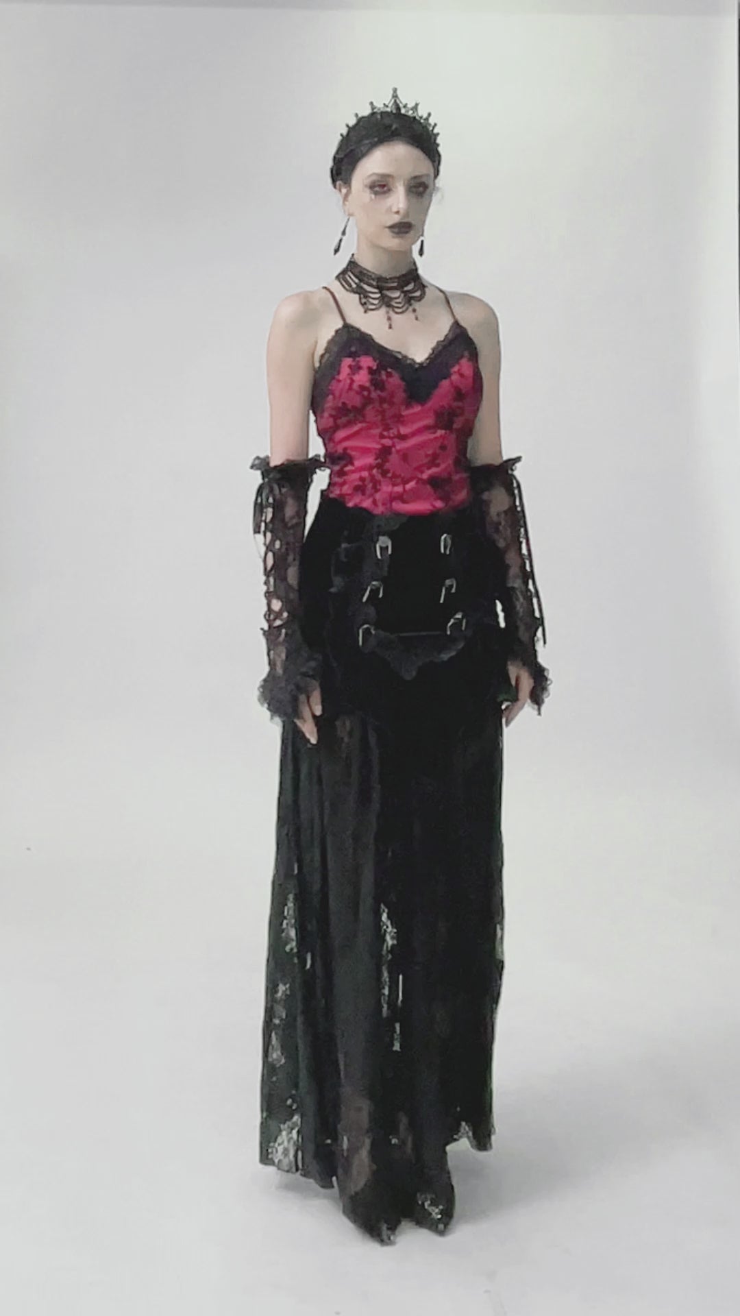Model in a lace-trimmed satin corset top with floral detail, styled in gothic fashion featuring long black skirt.