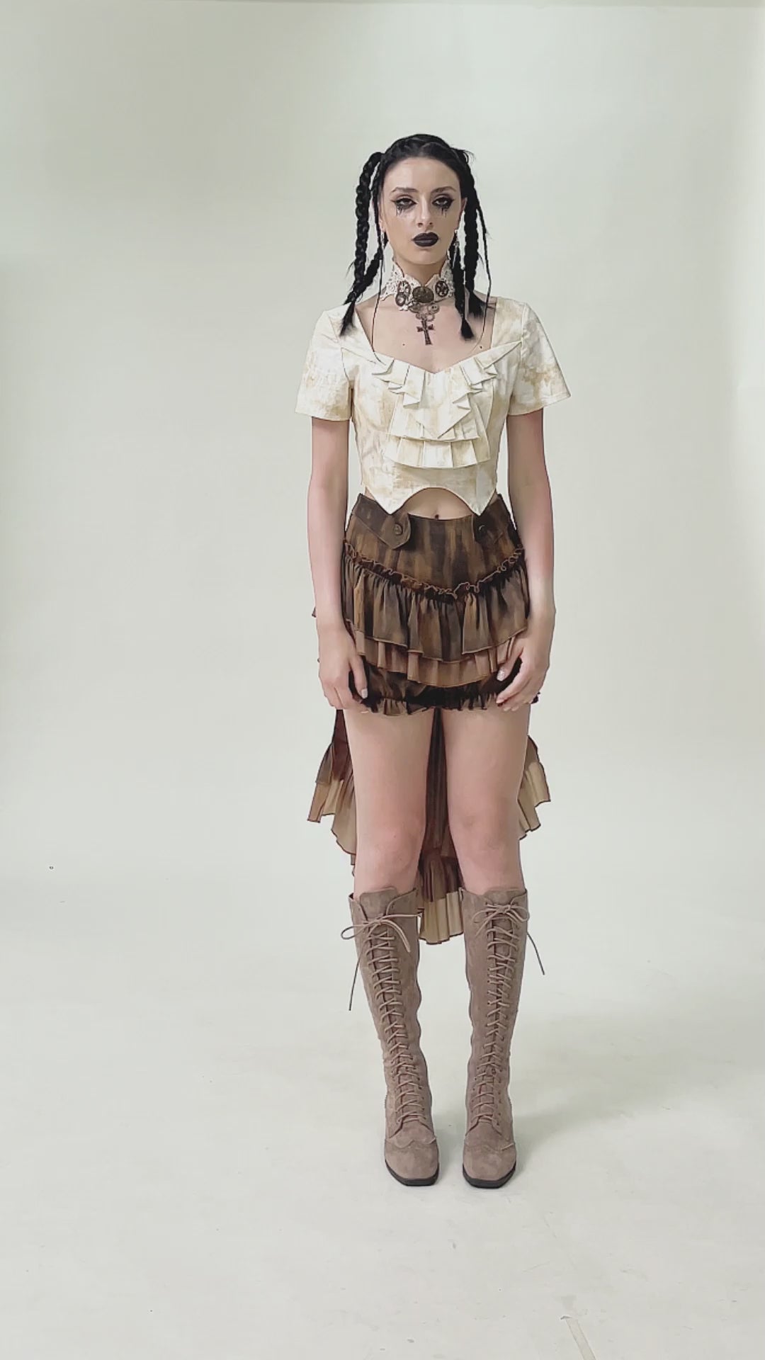 Model wearing brown steampunk ruffled skirt shorts with layered design and long back hem, paired with lace-up boots.