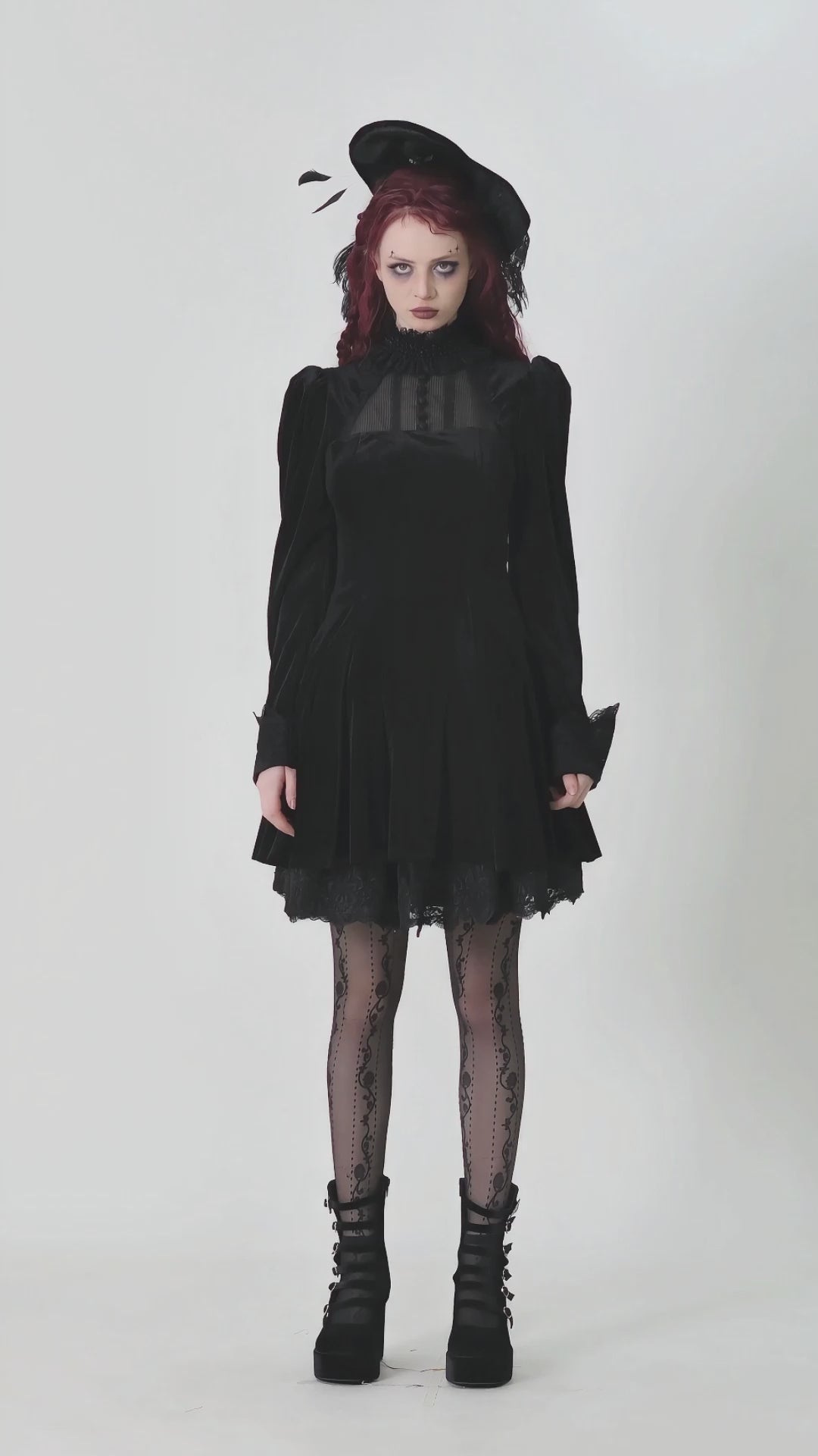 Model wearing a gothic black velvet dress with ruffles, puff sleeves, and lace details, paired with lace tights and a hat.