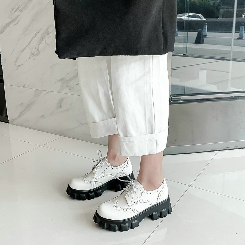 White PU leather platform shoes with square heel and round toe, complemented by stylish laces and paired with cropped white pants.