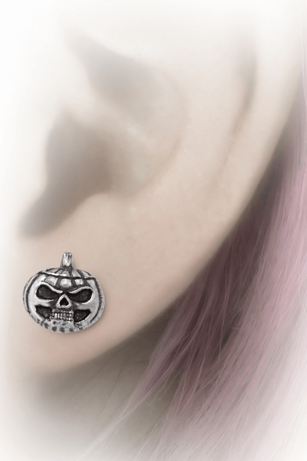 Gothic Pumpkin Skull Stud Earrings worn on an ear, perfect for Halloween and spooky occasions.
