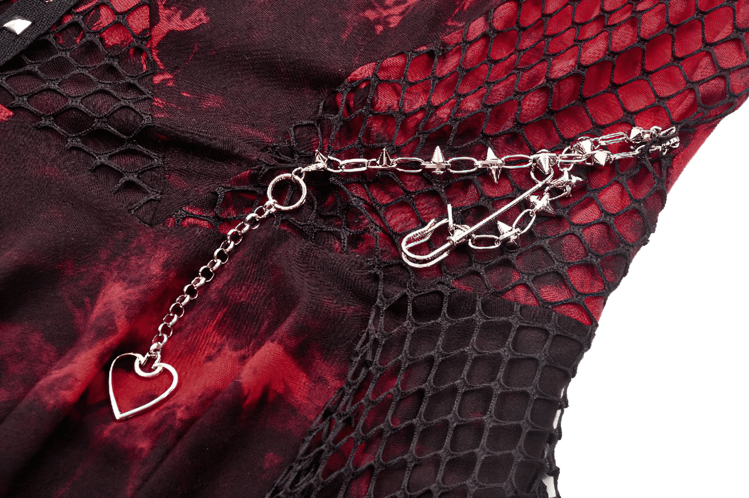 Detail of punk dress with fishnet, tie-dye pattern, and studded chain featuring heart charm.