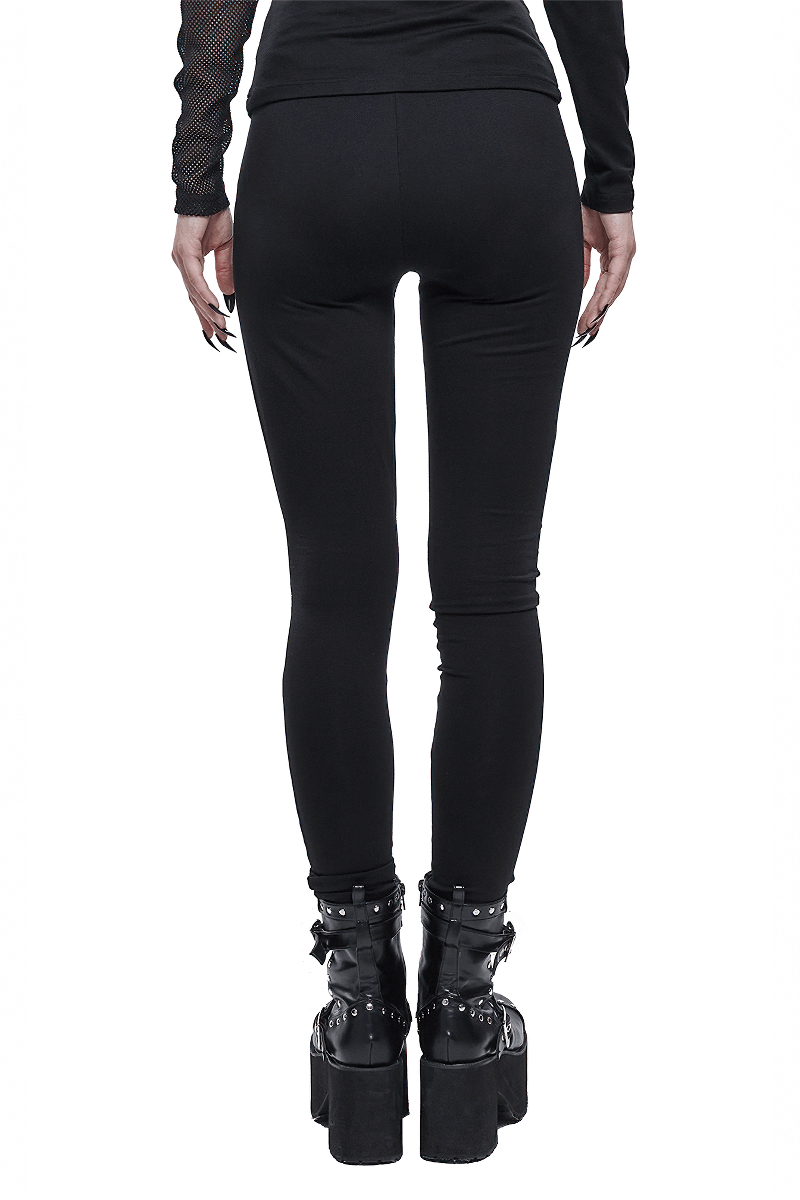 Back view of women's black asymmetrical leggings, showcasing punk style and flattering fit, paired with chunky platform boots.
