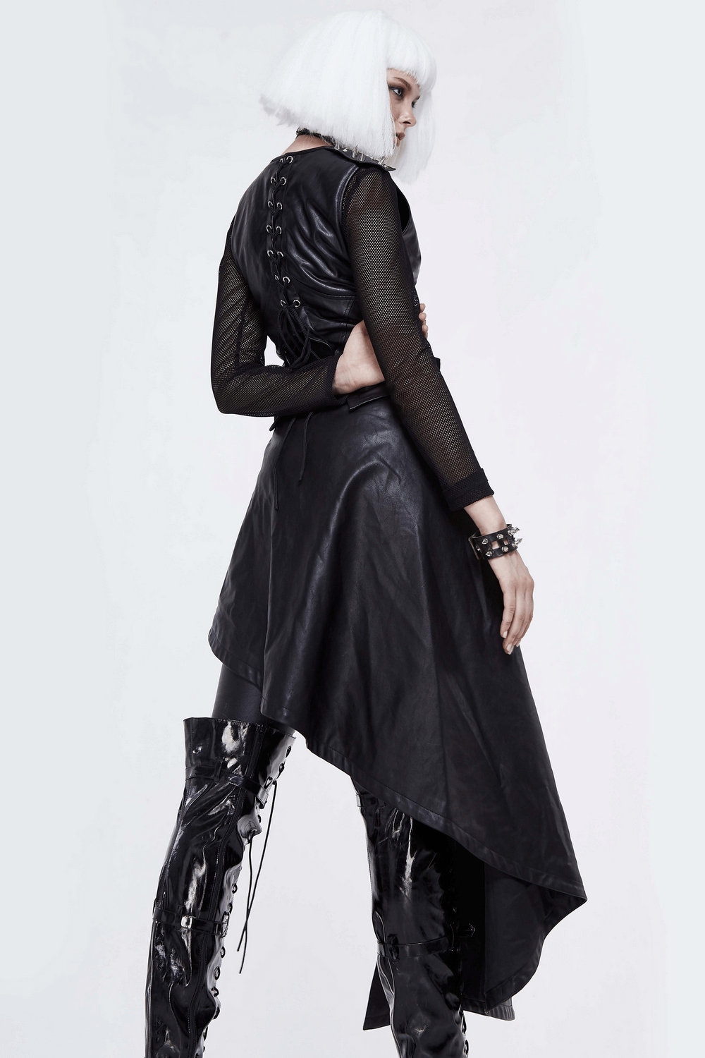 Model in a black asymmetrical PU leather dress with spiked details, showcasing punk fashion chic.