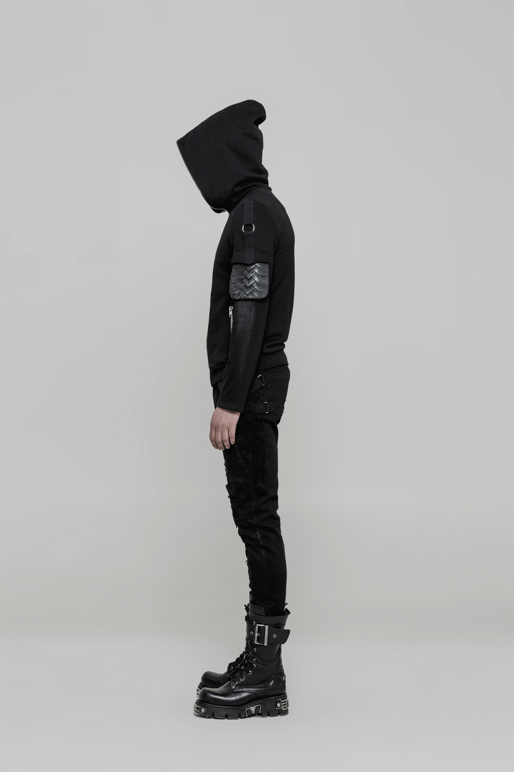Punk style model in black hoodie and trousers, showcasing edgy fashion with a side view.