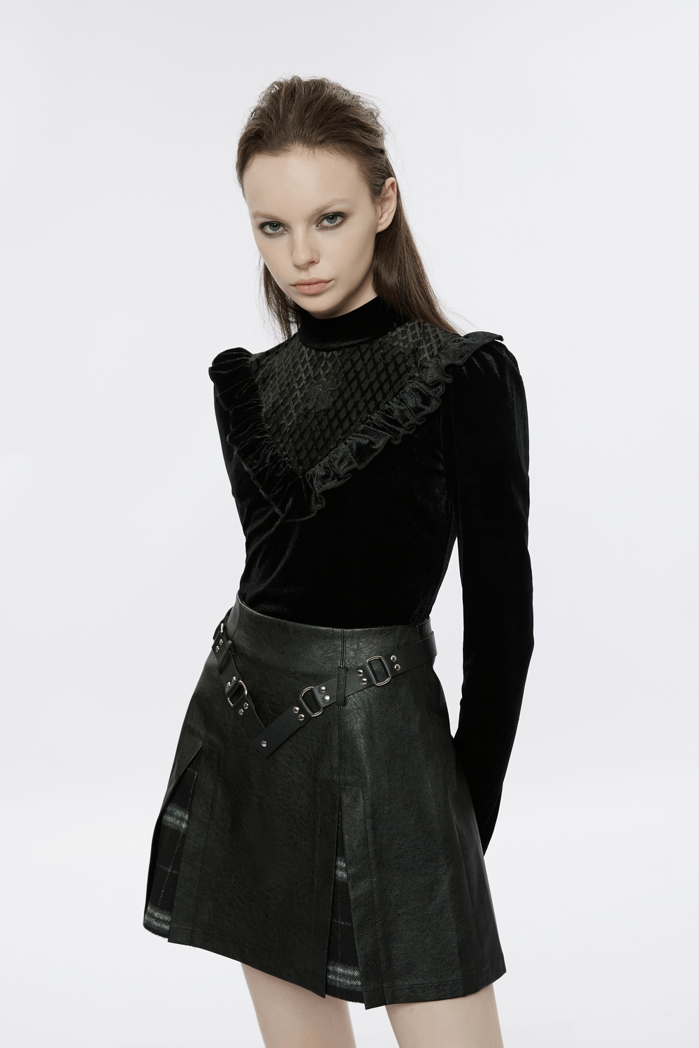 Model wearing punk black faux leather A-line mini skirt with plaid insert and ruffled black top.