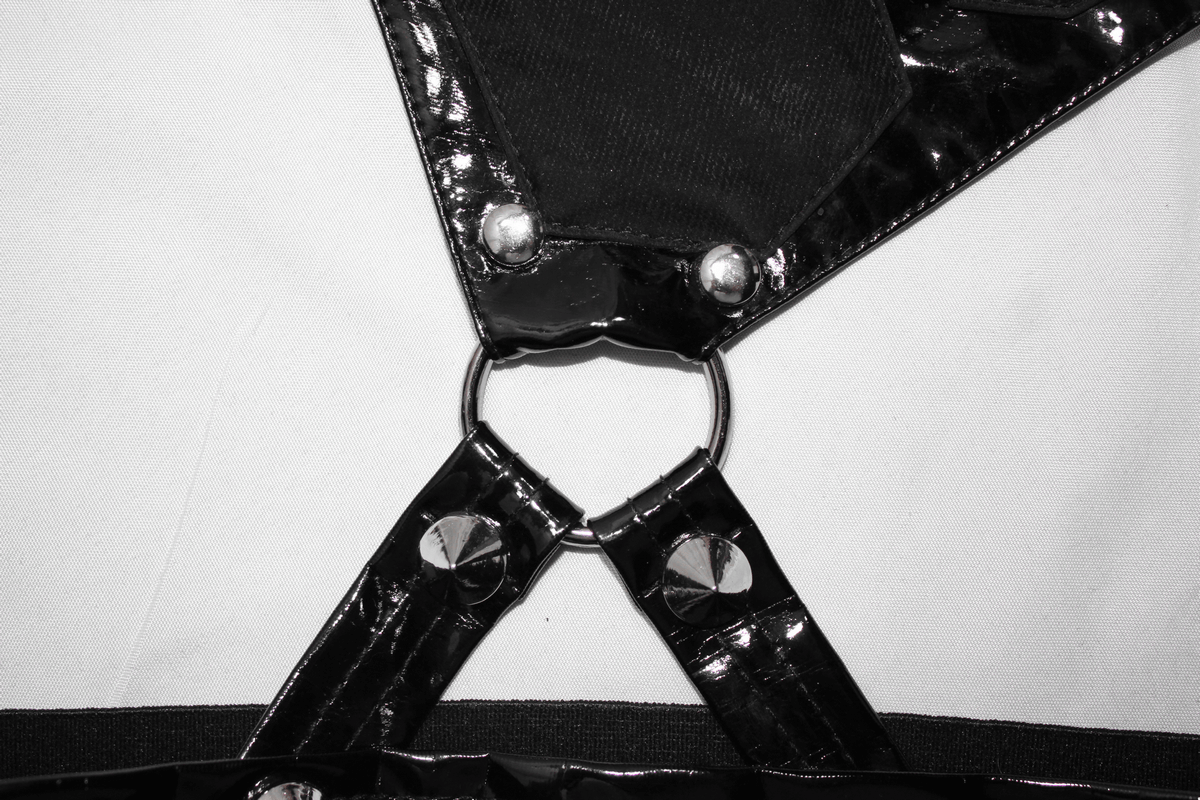 Close-up of punk black pants pentagram harness belts featuring glossy patent leather and silver rivets.