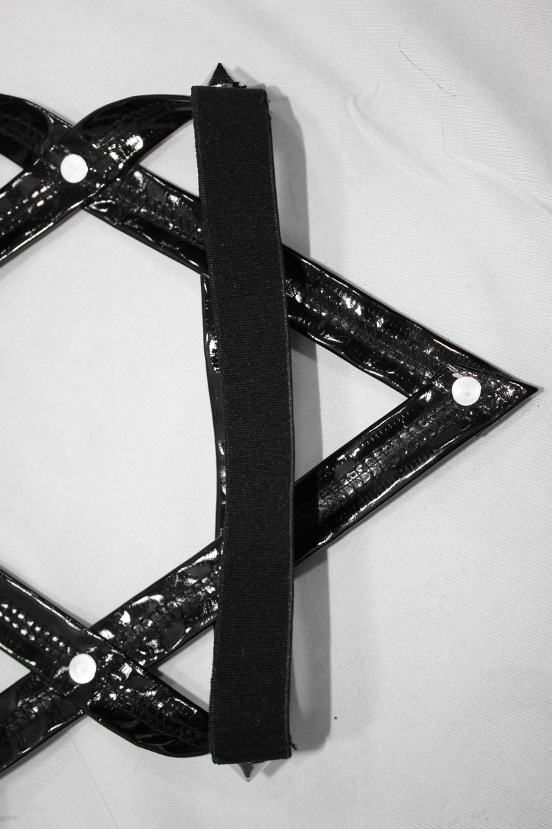 Close-up of a black pentagram harness belt with PU patent leather and silver metal rivets, showcasing unique punk style.