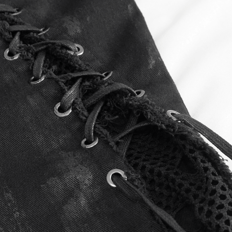 Close-up of punk trousers' hole net detailing and symmetrical lace-up in black fabric.