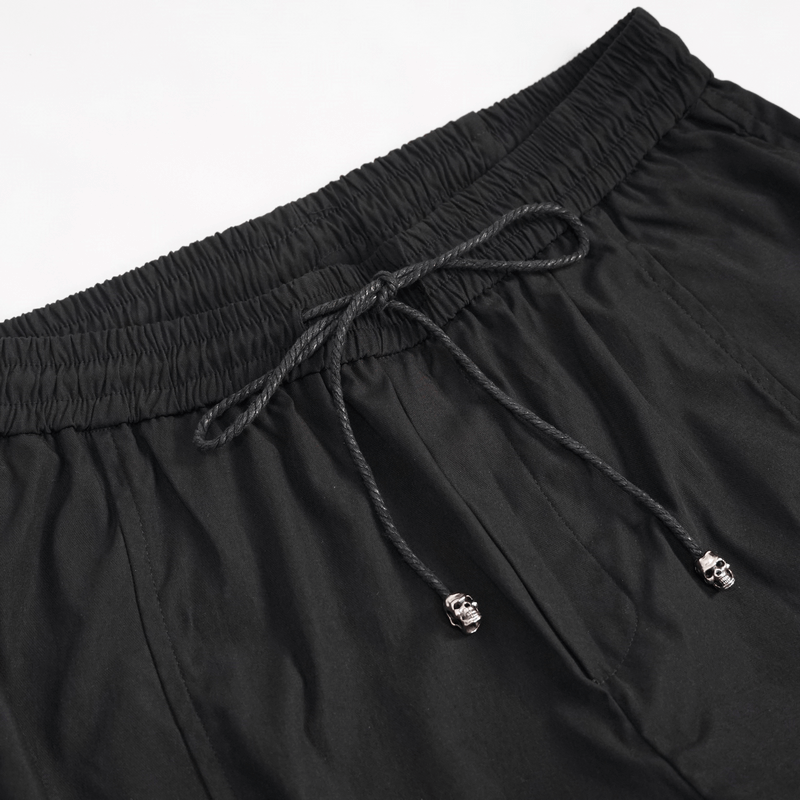 Close-up of black cargo pants waistband with elastic and skull drawstrings, showcasing punk style and comfort.