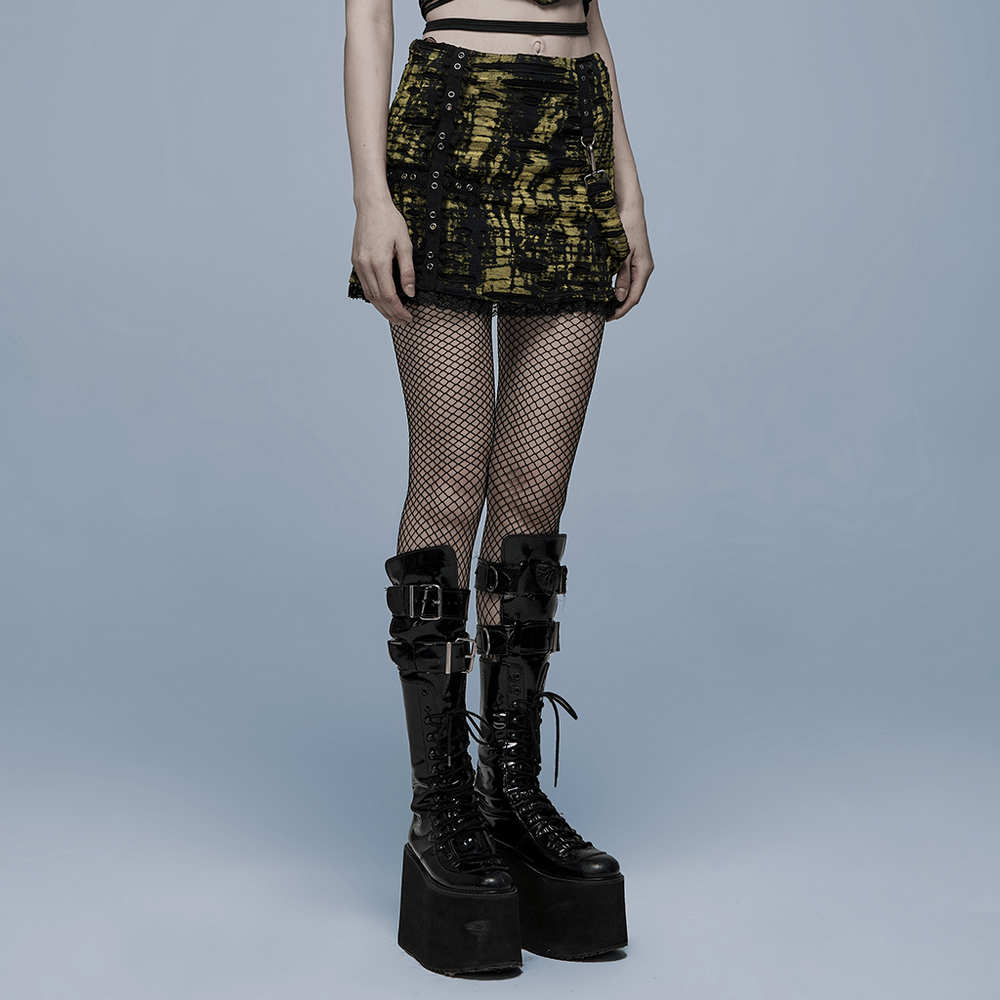 Gothic punk mini skirt featuring black and yellow mesh with distressed details and bold cross emblem, styled with fishnet tights.