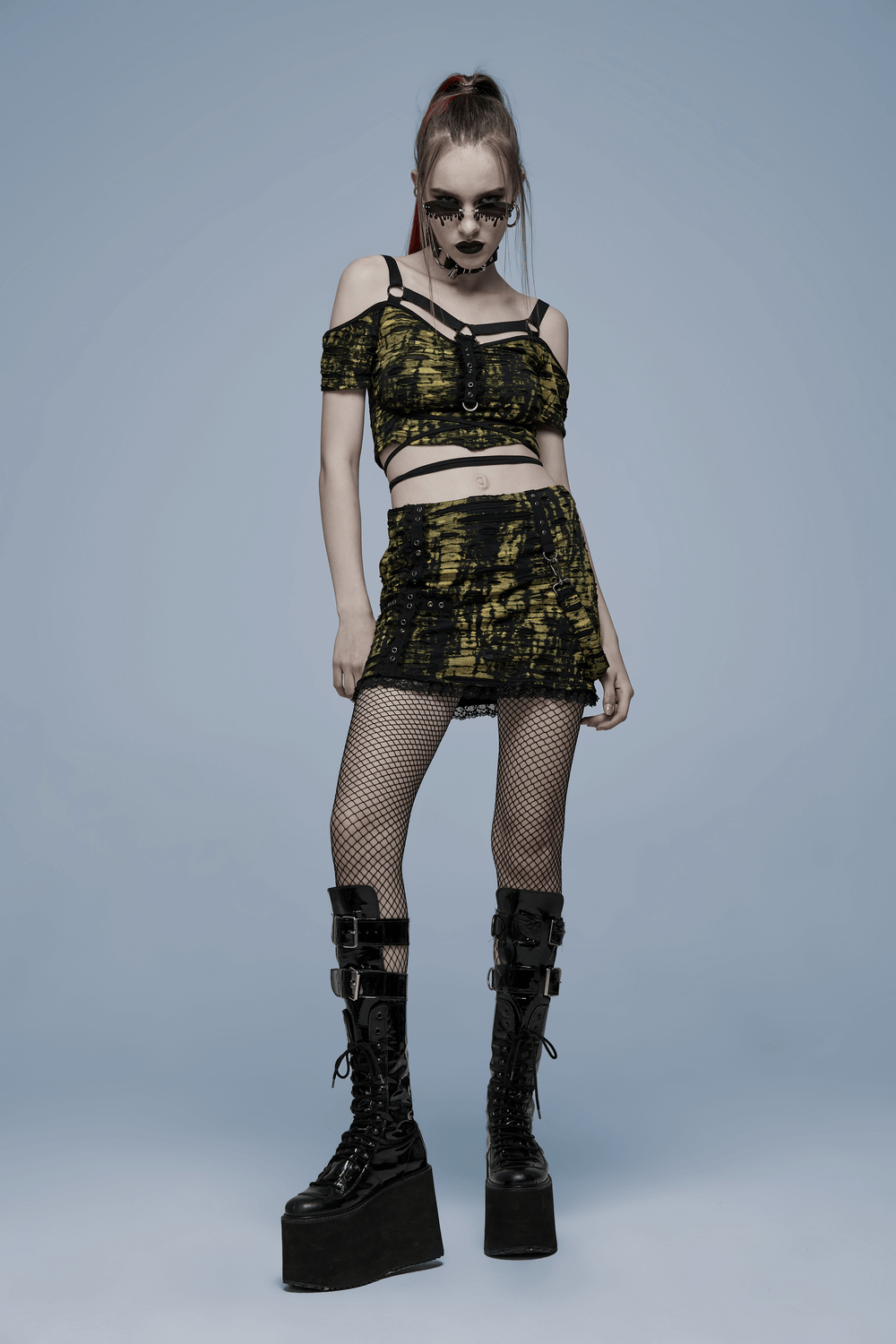 Punk cross dark knit mini skirt with a yellow and black design, paired with fishnet stockings and platform boots.