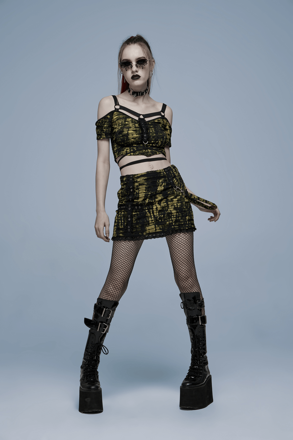 Punk Rave model in gothic yellow black mini skirt and crop top, showcasing edgy punk style with platform boots and fishnet.