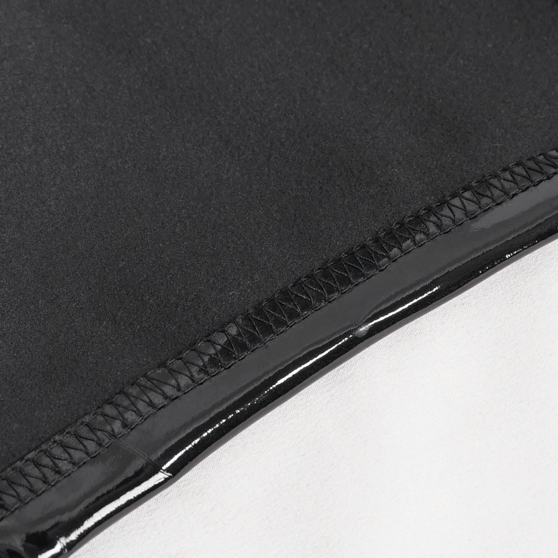Close-up of the seam detail on punk patent leather shorts, showcasing glossy black and contrasting white fabric.