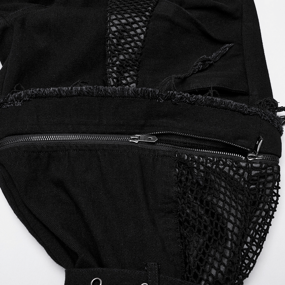 Close-up of punk pants with mesh pockets, zippers, frayed edges, and studded details, showcasing a bold fashion statement.