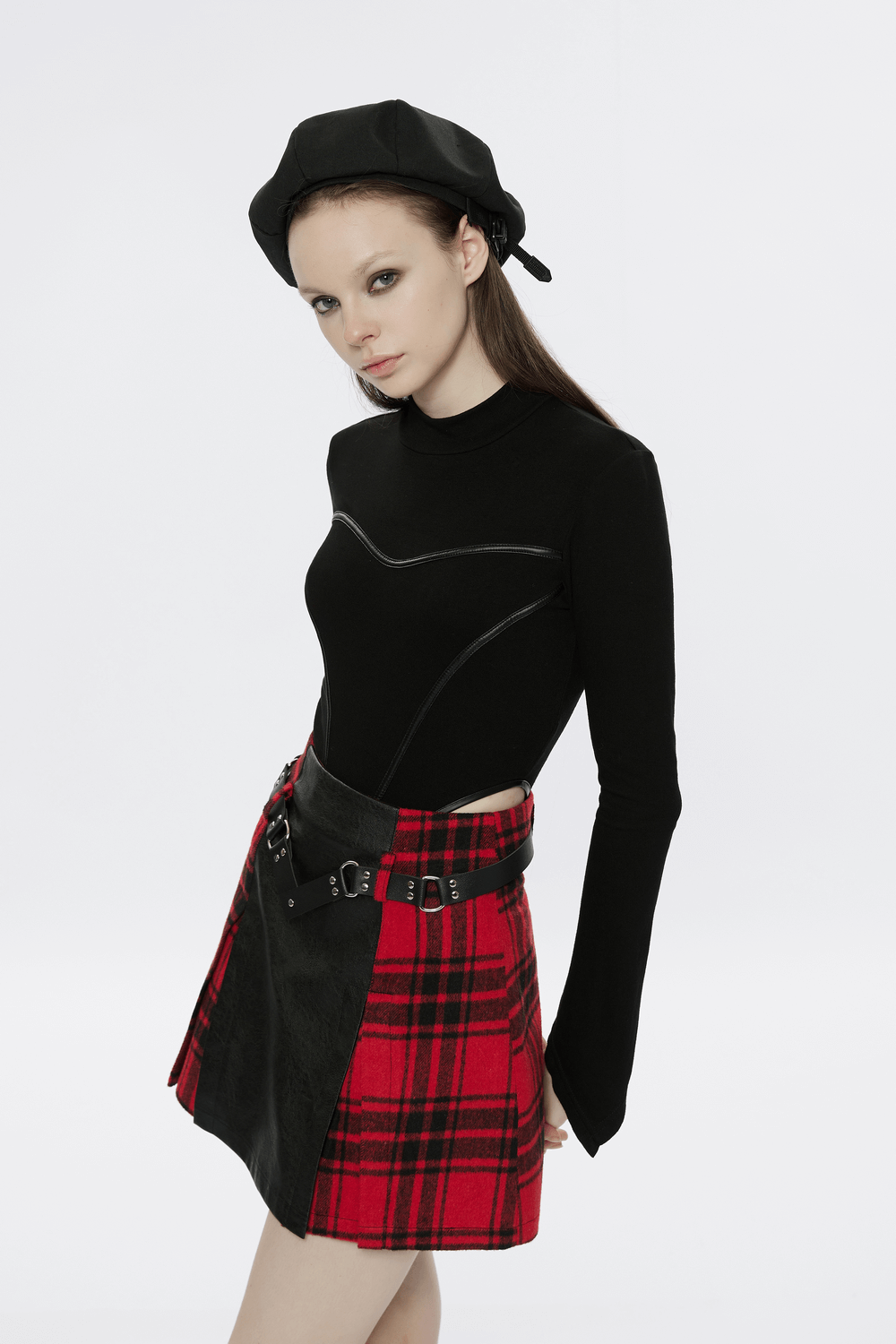 Model wearing a punk faux leather and plaid mini skirt with a rivet belt and stylish black top and beret.