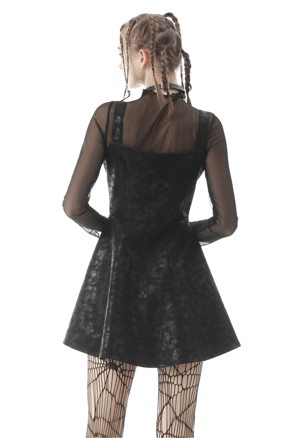 Back view of a punk faux leather mini dress with strap details, styled with a sheer top and fishnet tights.
