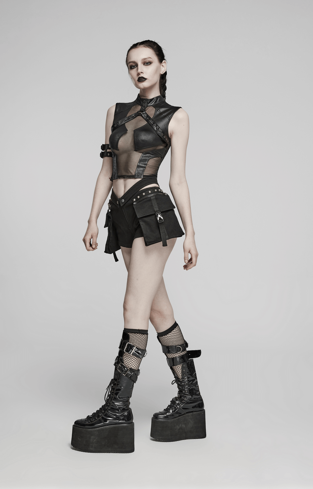 Punk female model wearing black riveted shorts with detachable cargo pockets and edgy platform boots.