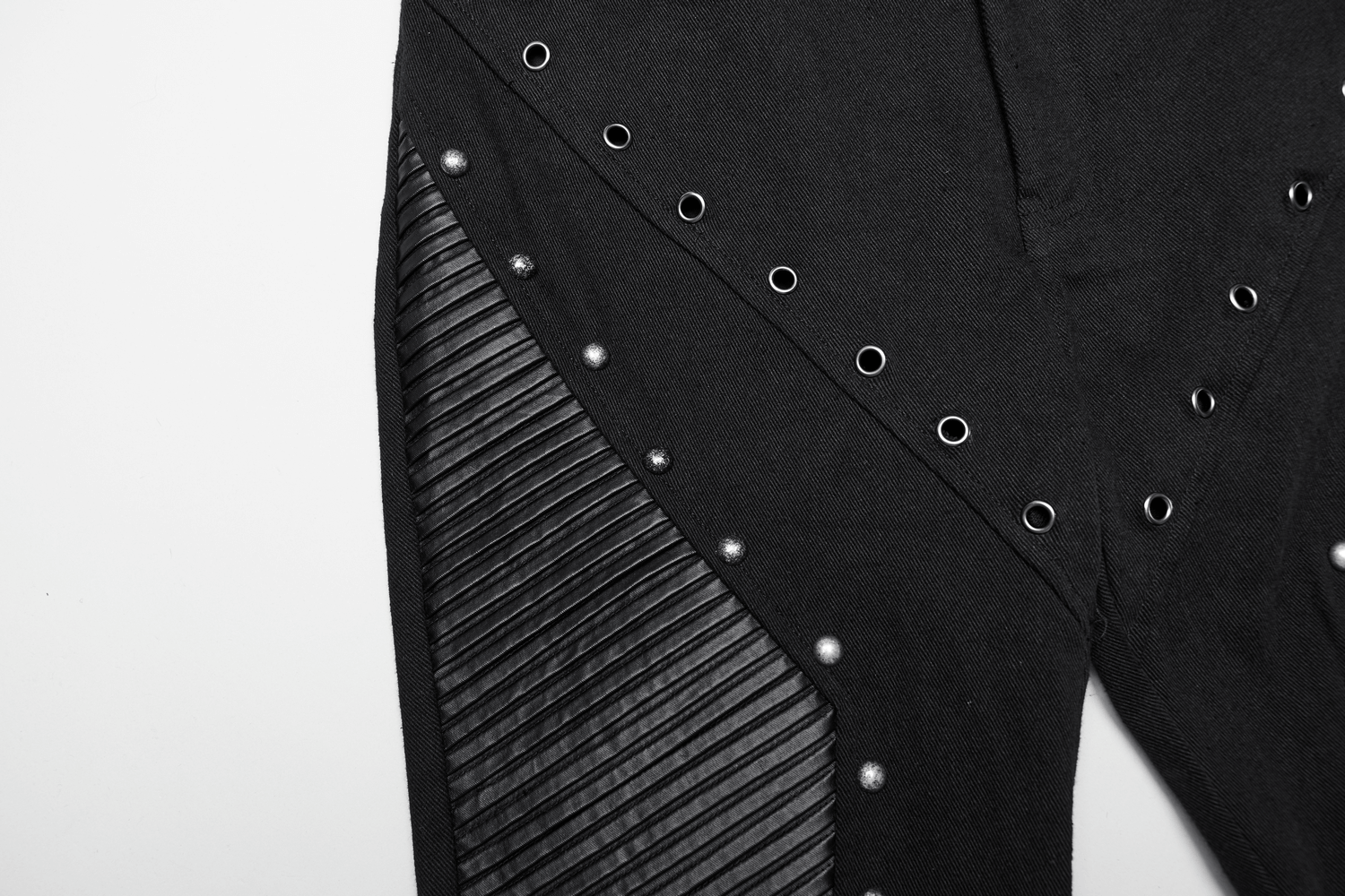 Close-up of punk flare trousers showcasing rivets and leather panels in black.