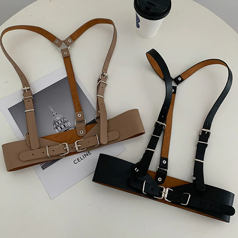 Punk gothic adjustable strap belts for women in black and brown on a table with coffee, showcasing stylish harness design.