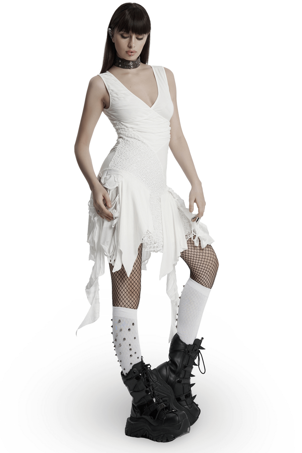 Punk-inspired white sleeveless dress with V-neck, mesh details, and irregular hem, styled with edgy black boots.