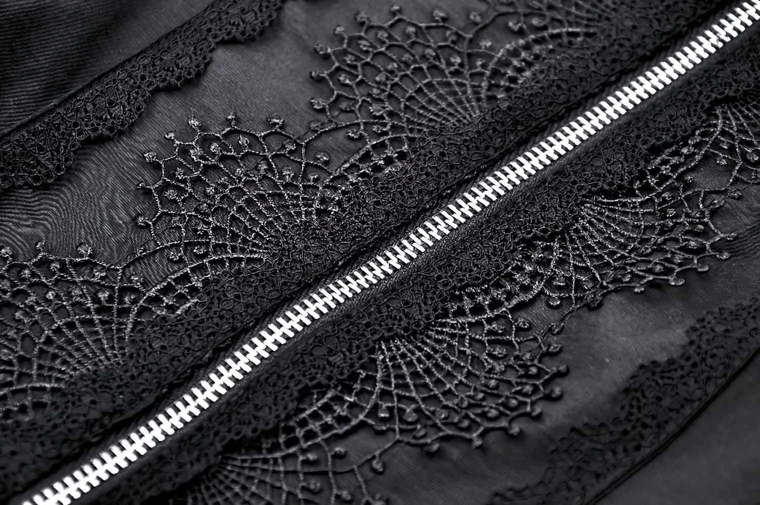 Close-up of intricate lace and spider web cutout detailing on a black gothic punk blouse.
