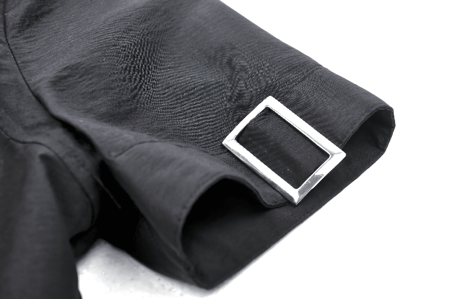 Close-up of black blouse sleeve with silver buckle detail, showcasing punk style and edgy design elements.