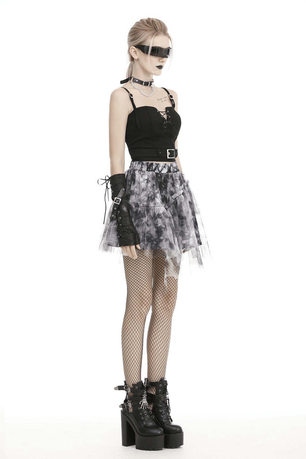 Punk model in lace-up front corset, metallic buckle, tulle skirt, fishnet tights, and platform boots for edgy style.