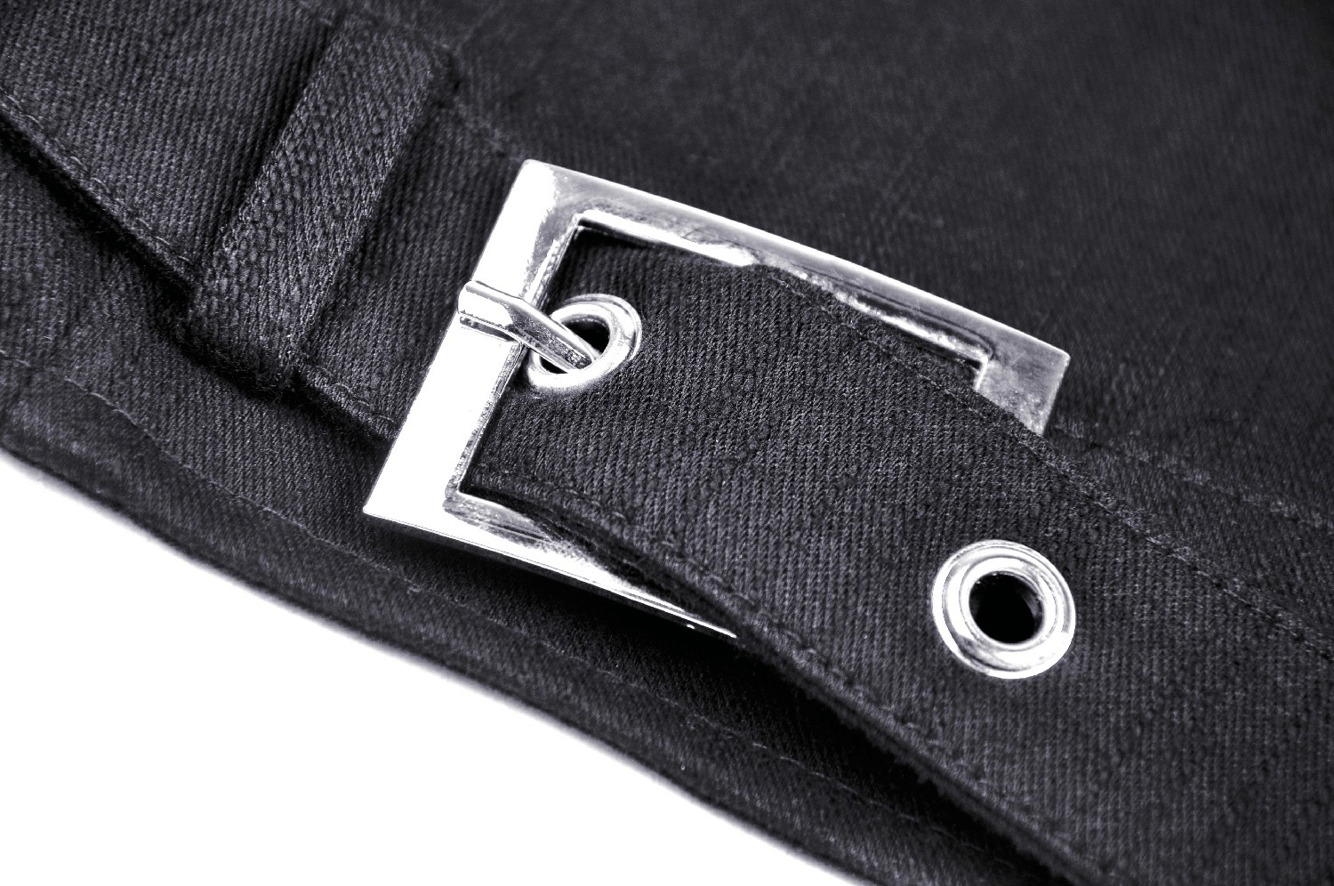 Close-up of a metal buckle on a black fabric strap, showcasing punk fashion details.