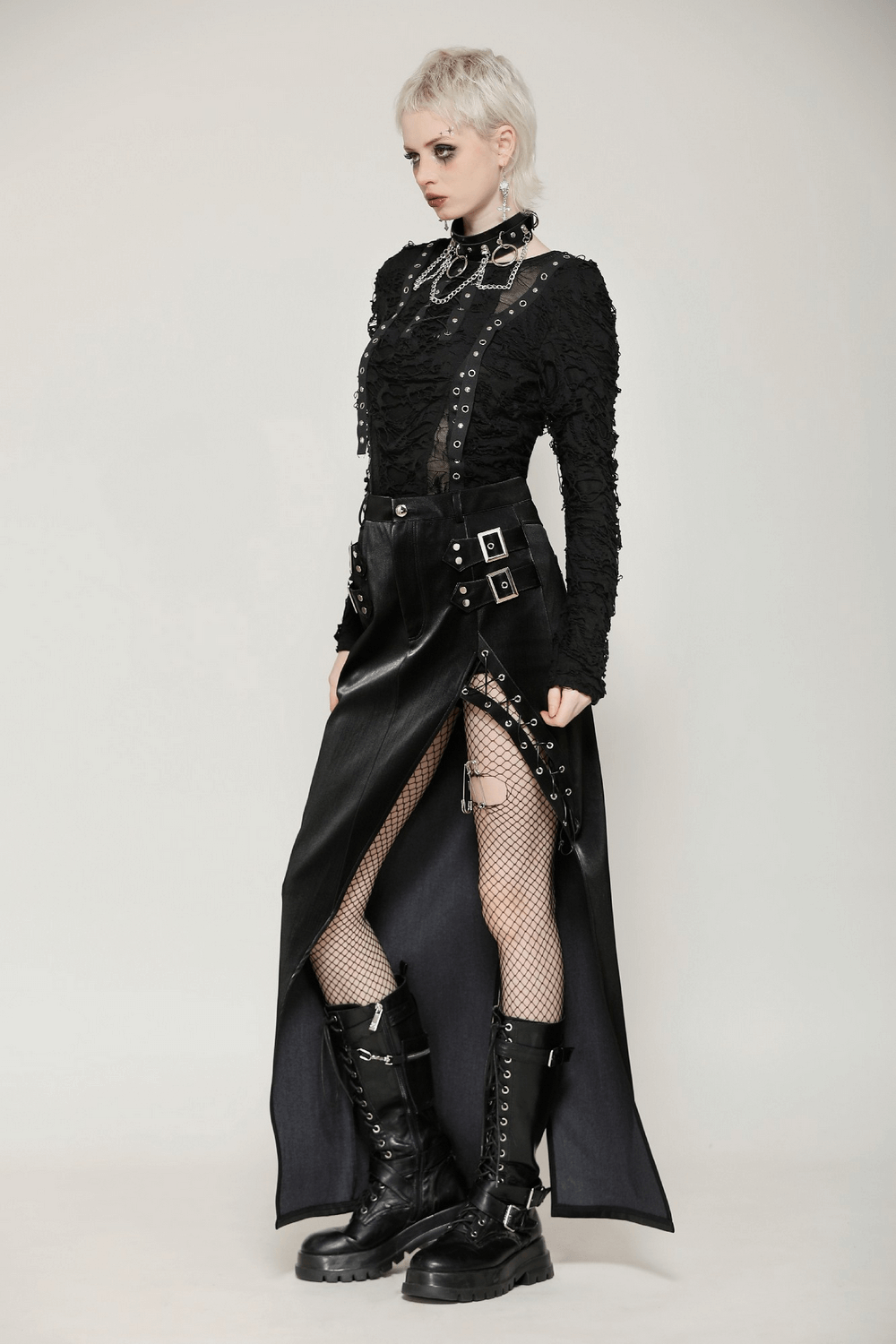 Edgy model in punk gothic outfit featuring a black lace-up top, fishnet stockings, and bold leather boots.