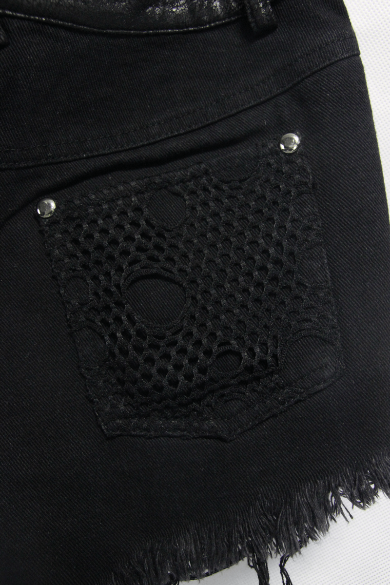 Close-up of black ripped women's shorts with a fishnet pocket design, showcasing punk style and edgy fashion.