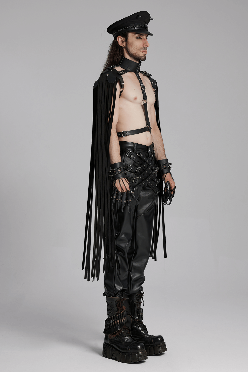 Edgy male model in punk leather tassel shoulder armor and halter neck harness, showcasing a bold, rebellious look.