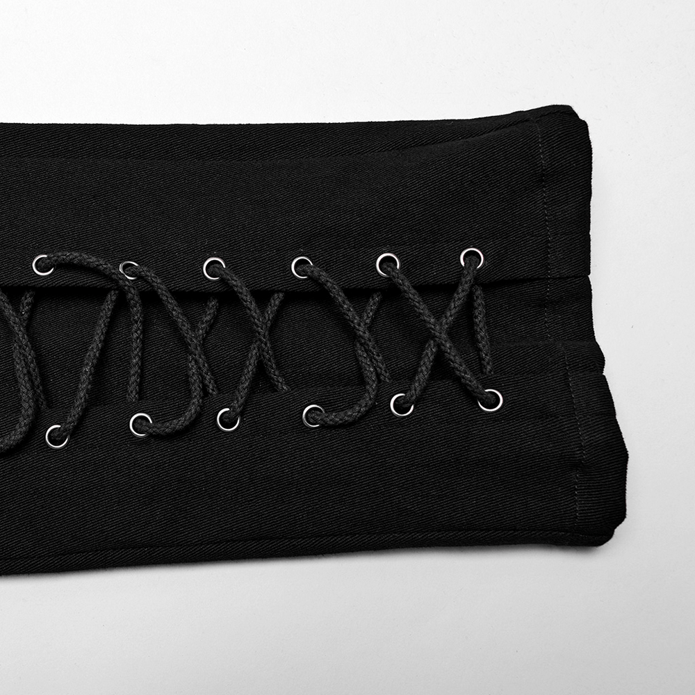 Close-up of punk men's black twill pants with eyelets and drawstrings detail.