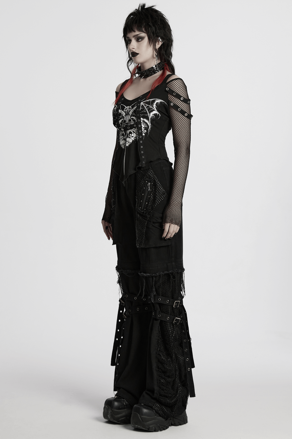Gothic model in punk mesh sleeved top featuring bat print, black baggy pants, and bold accessories.
