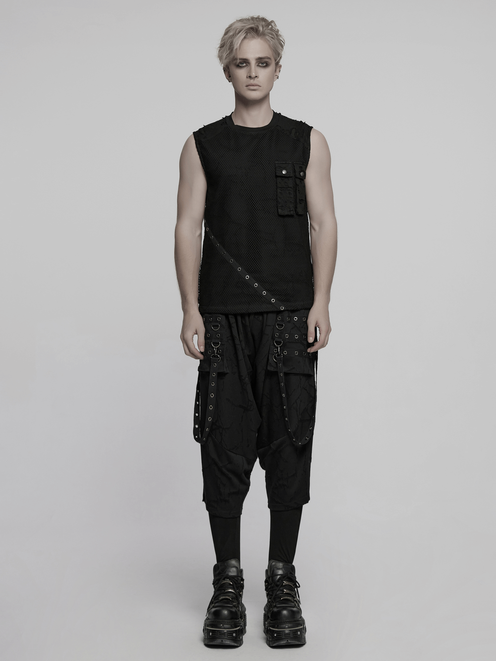 Stylish punk mesh top with tattered details and pockets, paired with edgy black pants and chunky boots.