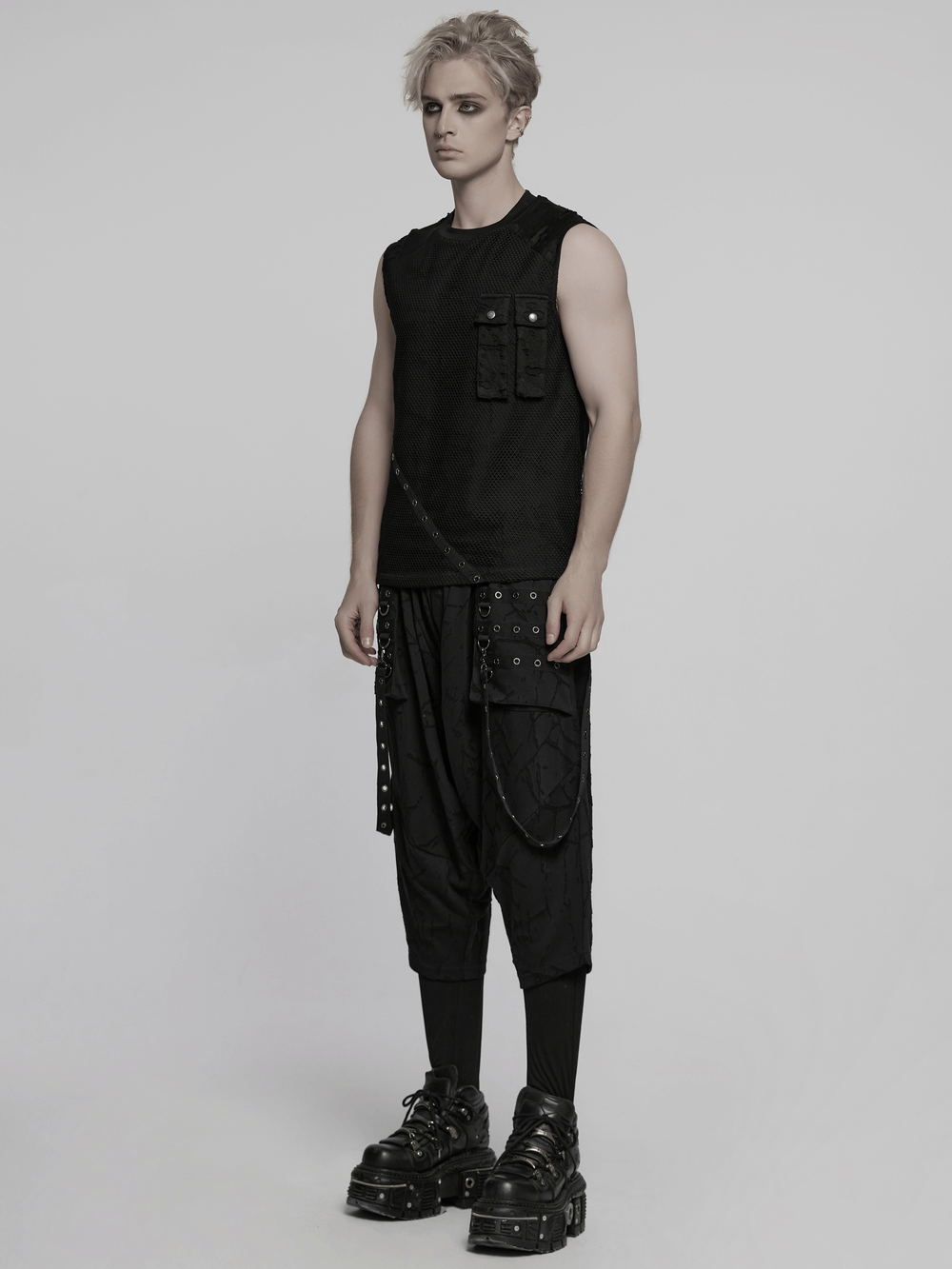 Punk mesh top with tattered fabric and pocket details paired with edgy black pants and chunky shoes.