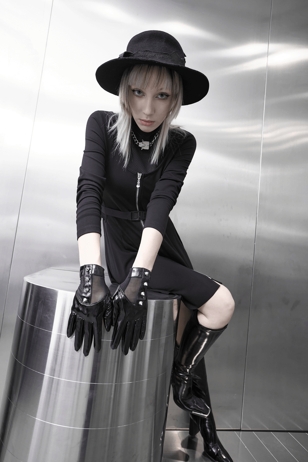 Fashion model showcasing Punk Metal Rivet PU Leather Gloves with stylish black outfit and hat in modern setting.