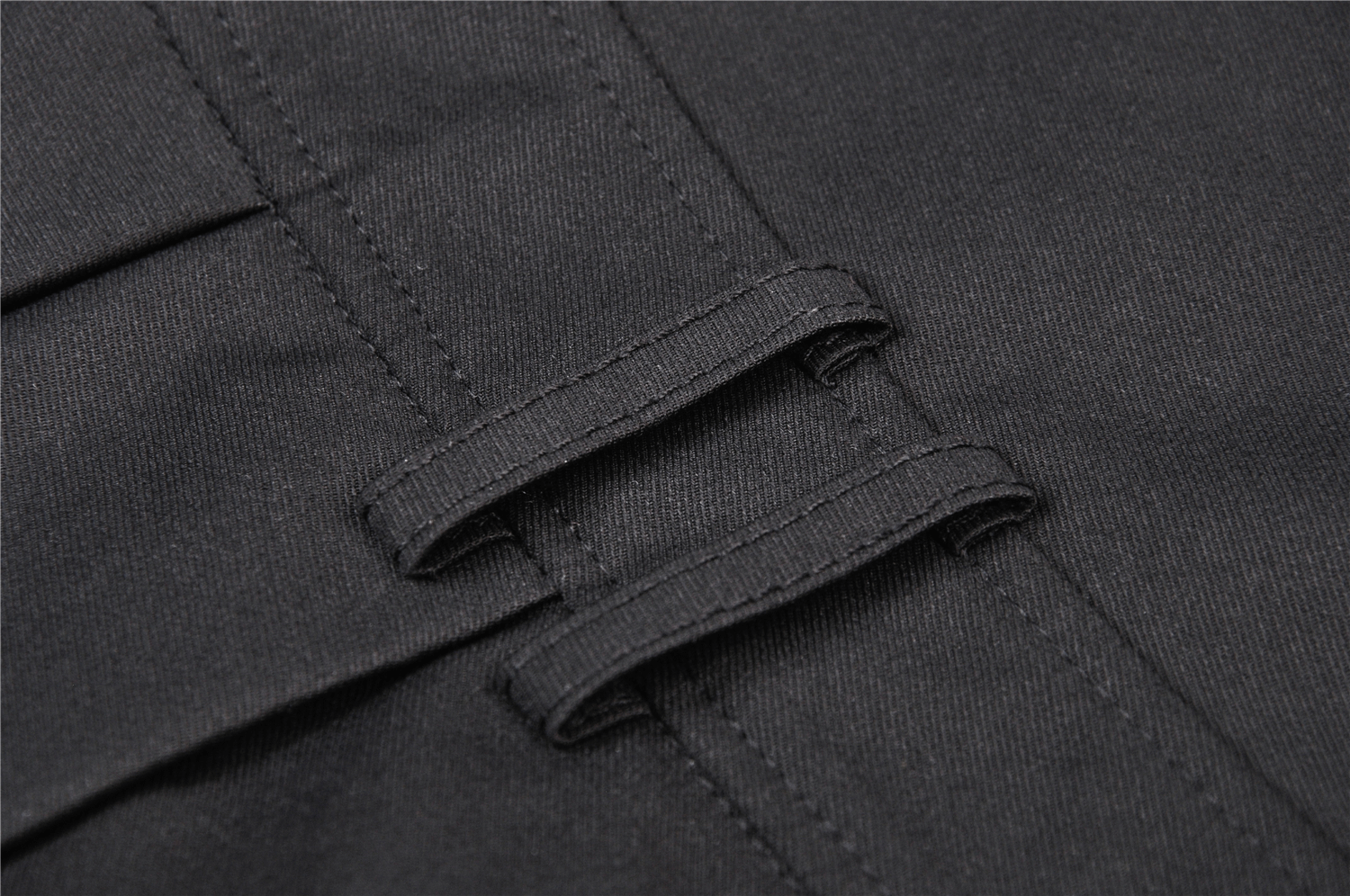 Close-up of black fabric with stylish stitching and suspender straps, perfect for a punk-inspired look.