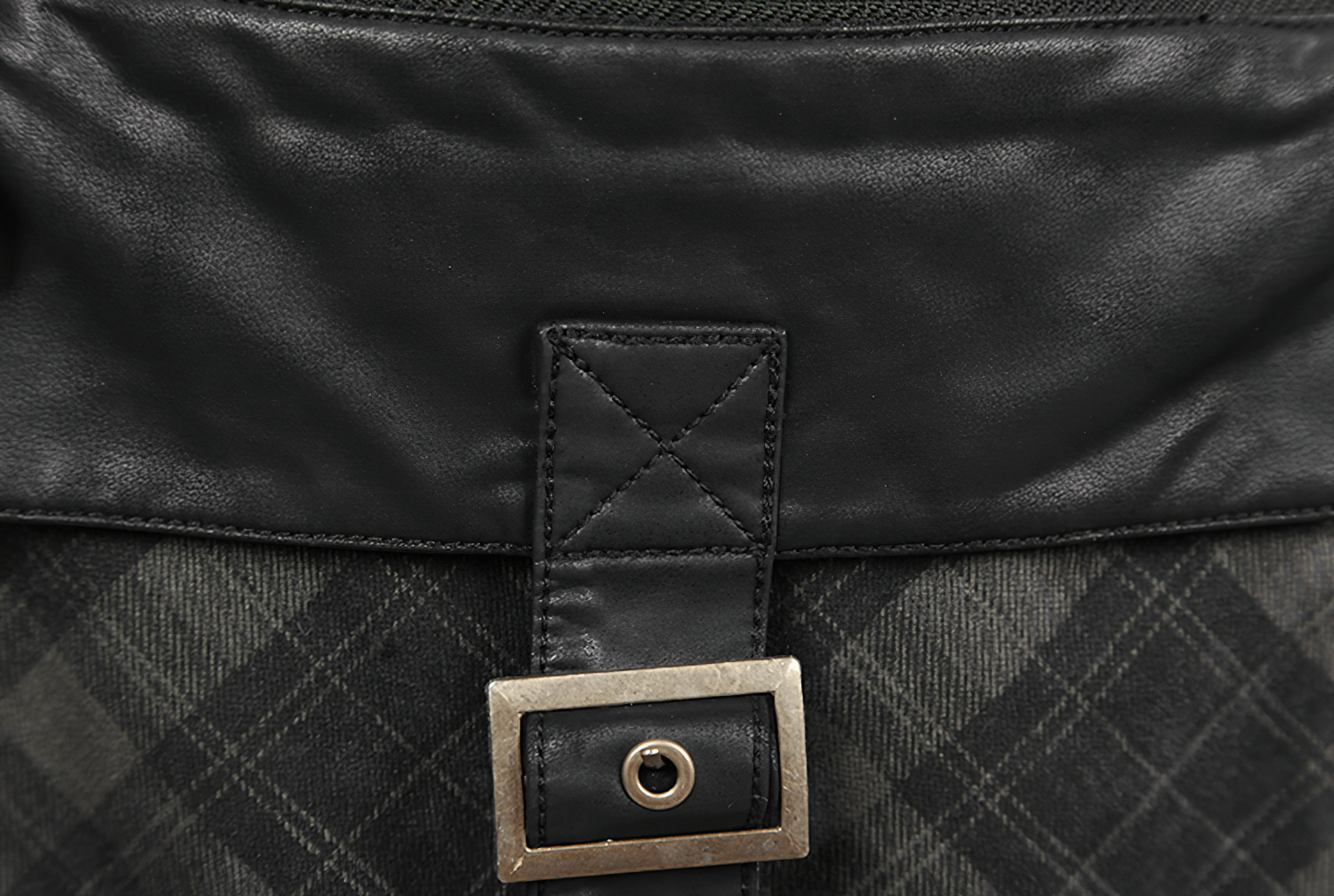 Close-up of punk plaid kilt's black leather waistband and unique fastener detail.