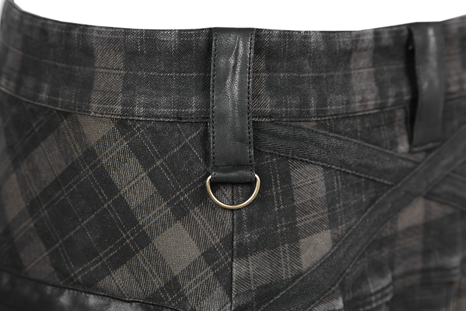 Close-up of the waistband of a black plaid kilt featuring leather details and a gold ring loop.