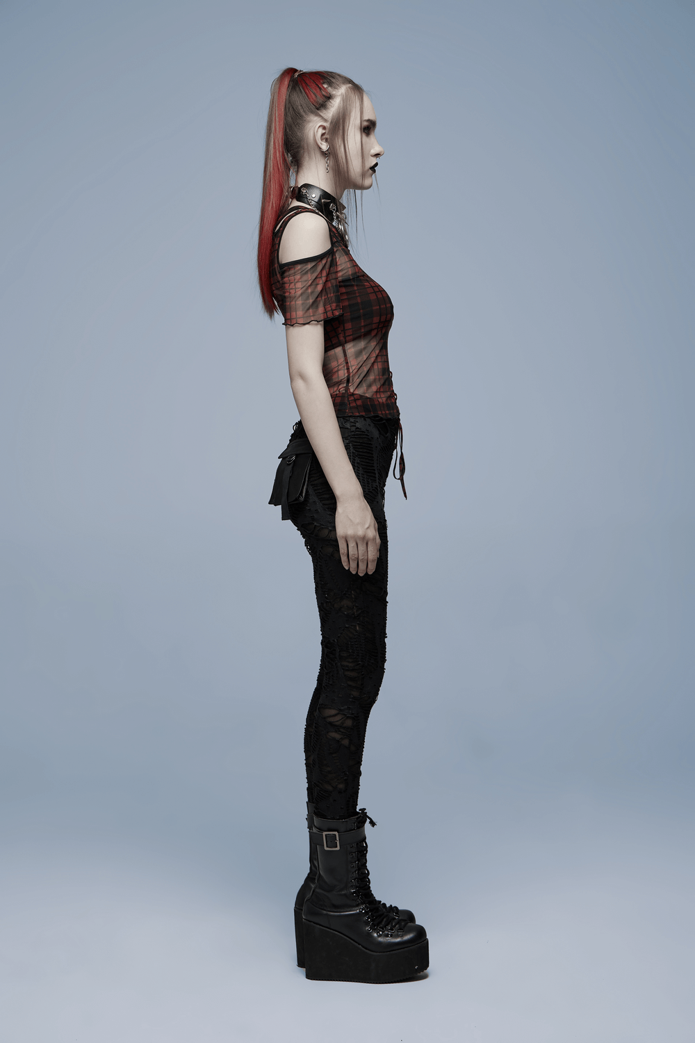 Side view of a woman in a punk plaid mesh off-shoulder T-shirt, showcasing a stylish edgy look with platform boots.