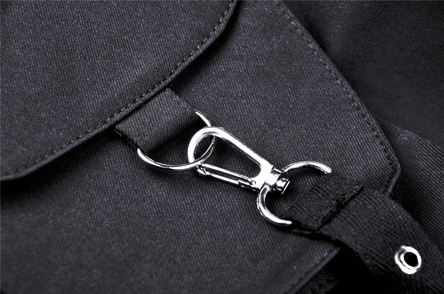 Close-up of a metal clasp on a black fabric bag, showcasing stylish hardware details.