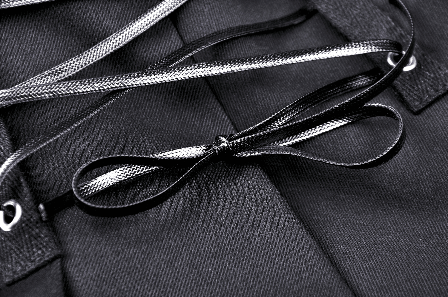 Close-up of black and silver laces on punk pleated mini skirt, showcasing edgy design and stylish details.