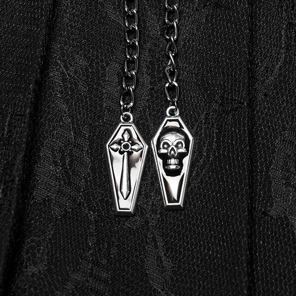 Close-up of detachable coffin pendant chains from a punk pleated skirt, featuring skull and floral designs.