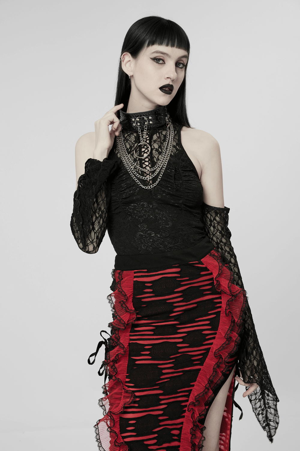 Gothic fashion model in a black lace bodysuit and red striped skirt, showcasing edgy punk style.