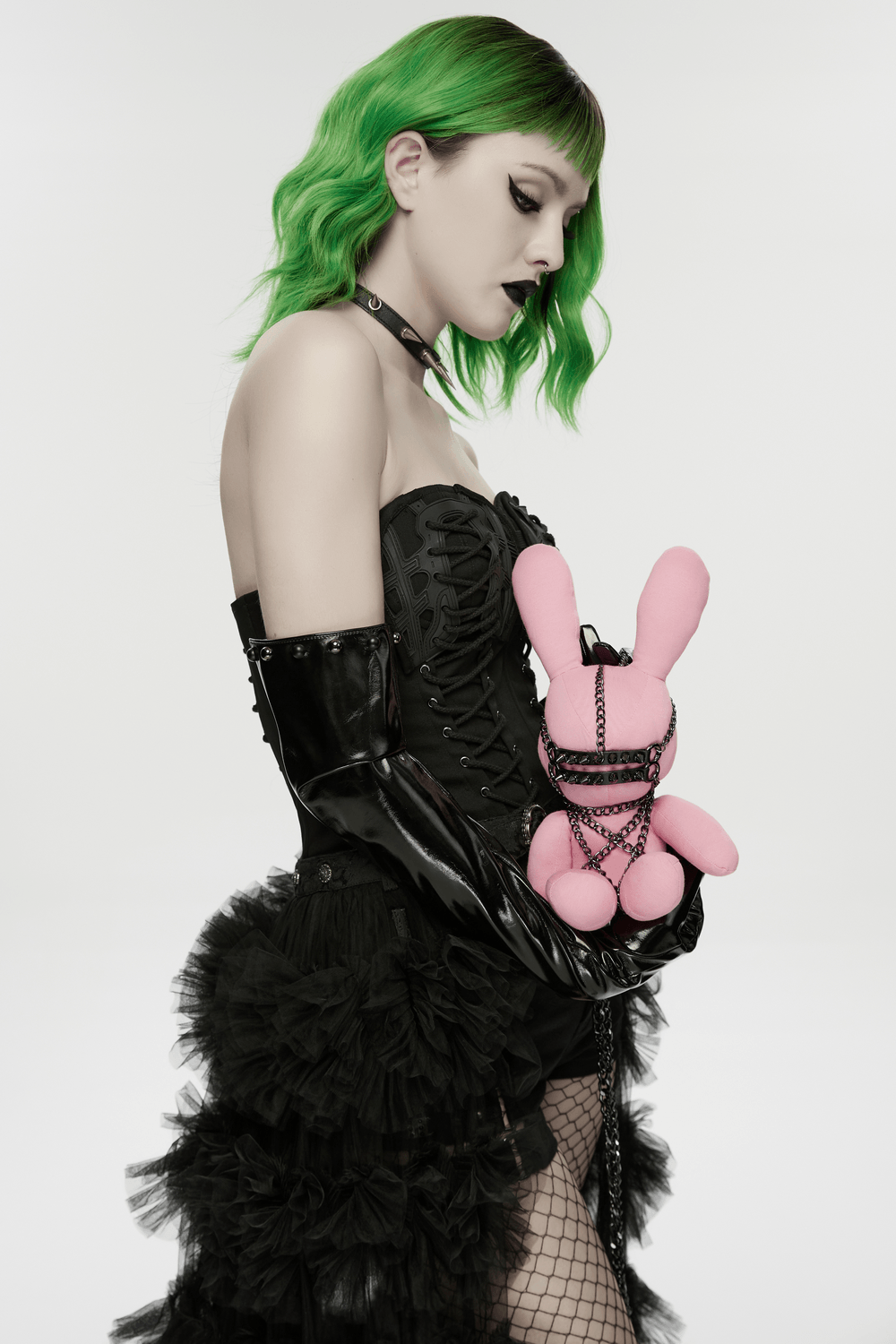 Alt Tag: Punk Rabbit Plush Chain Waist Accessory Charm held by model in black gothic corset, green hair, punk style studio photo