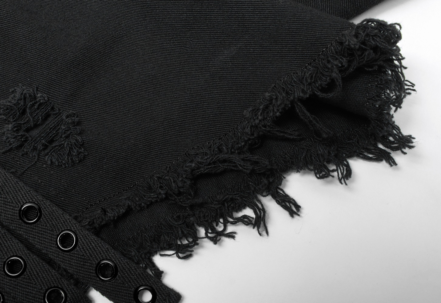 Close-up of black denim fabric showing frayed edges and eyelets, perfect for punk gothic style shorts.