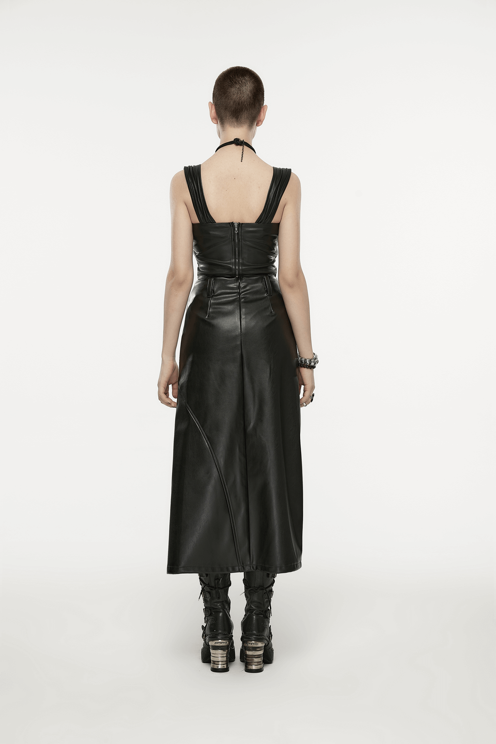Back view of a model in a sleek black faux leather A-line dress with stylish straps and dramatic silhouette.