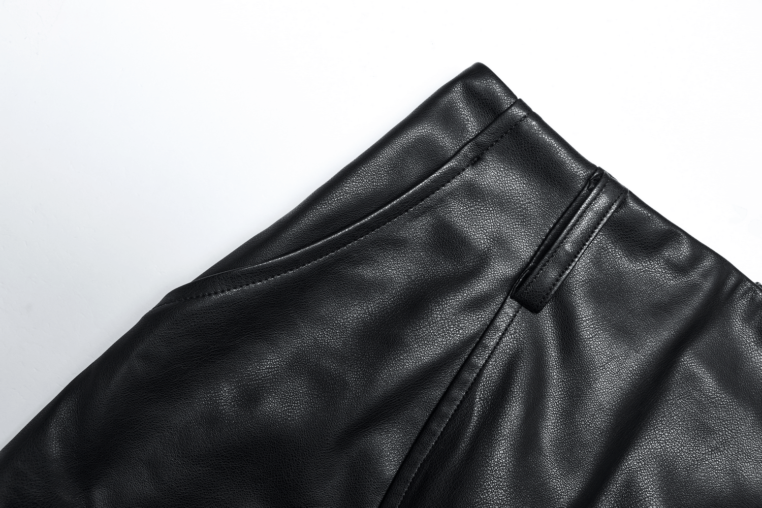 Close-up of the high waist detail on a black faux leather A-line skirt showcasing its sleek design.